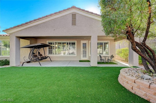 back of house featuring a lawn and a patio area