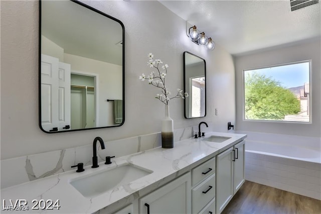 bathroom with tiled bath, vanity, and hardwood / wood-style flooring