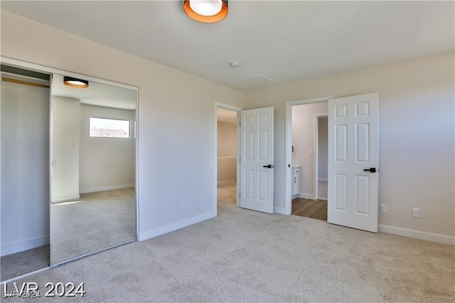 unfurnished bedroom with light colored carpet and a closet