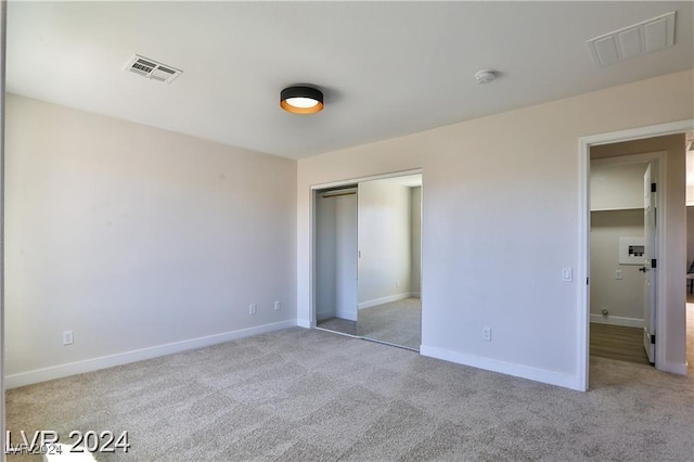 unfurnished bedroom featuring light carpet and a closet