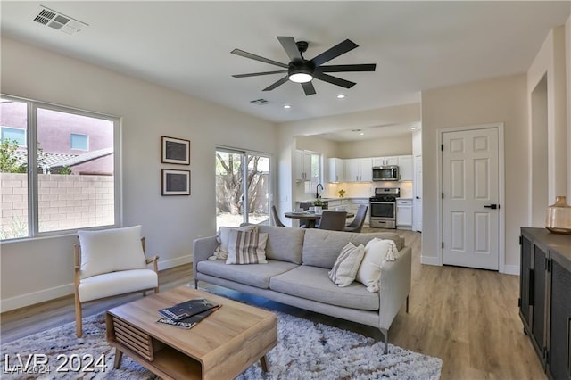 living room with ceiling fan, light wood-type flooring, and sink