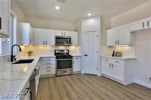 kitchen featuring white cabinets, appliances with stainless steel finishes, light wood-type flooring, and sink