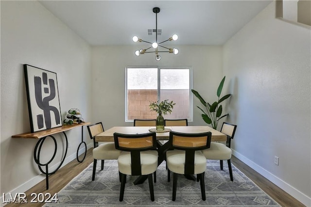 dining area featuring dark wood-type flooring and a notable chandelier