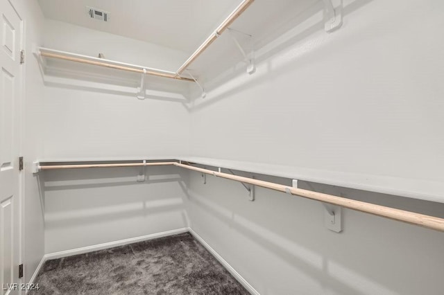 walk in closet with dark carpet