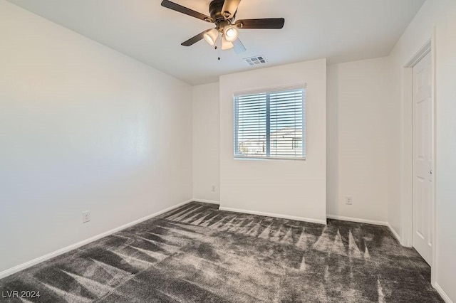 empty room featuring dark carpet and ceiling fan