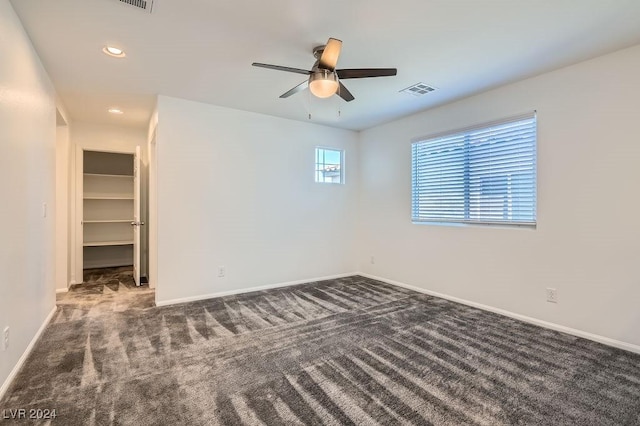 unfurnished room with dark colored carpet and ceiling fan