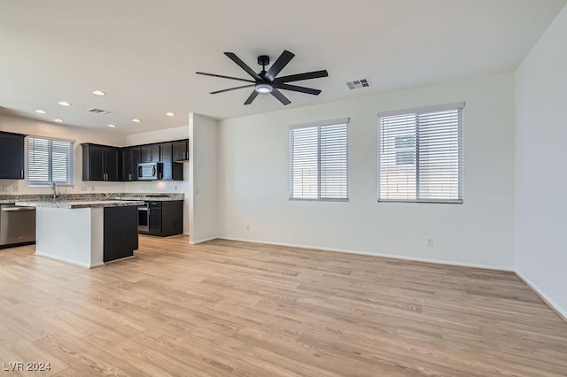 kitchen featuring a kitchen island, light wood-type flooring, a healthy amount of sunlight, and appliances with stainless steel finishes