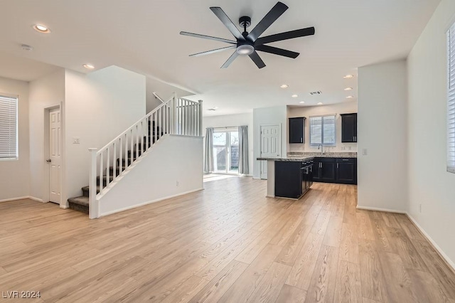 unfurnished living room featuring ceiling fan, sink, and light hardwood / wood-style floors