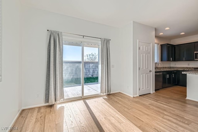 kitchen featuring stone counters, appliances with stainless steel finishes, light hardwood / wood-style floors, and sink