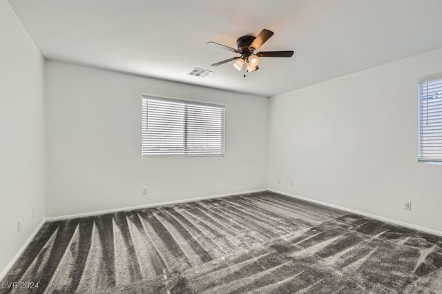 unfurnished room with ceiling fan and dark carpet