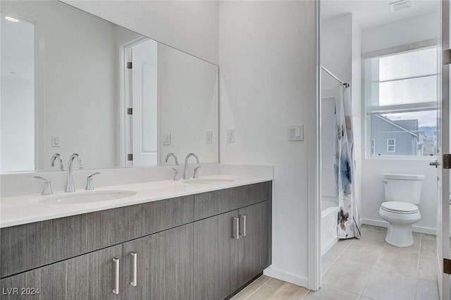 bathroom with double vanity, toilet, a sink, and tile patterned floors