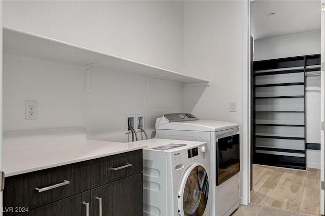 clothes washing area with light wood finished floors and washer and dryer