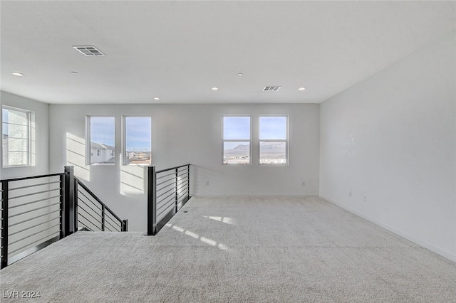 carpeted spare room with visible vents, plenty of natural light, and baseboards