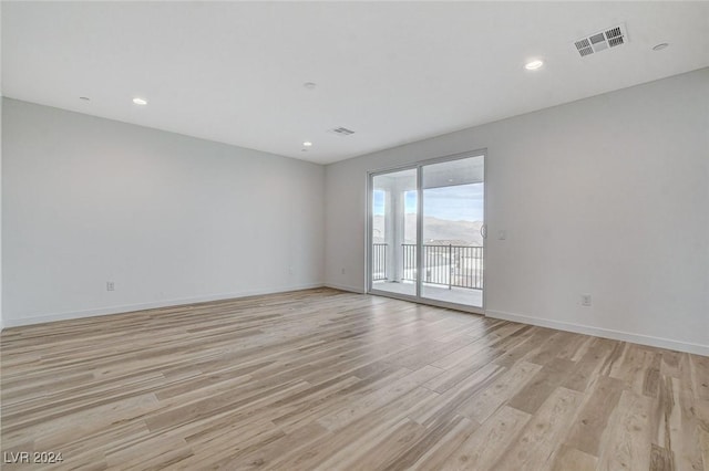 spare room featuring baseboards, visible vents, and light wood finished floors