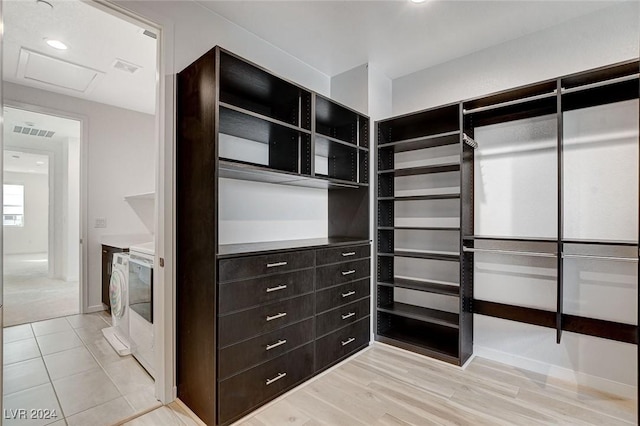 spacious closet featuring attic access, washer and dryer, light wood-type flooring, and visible vents