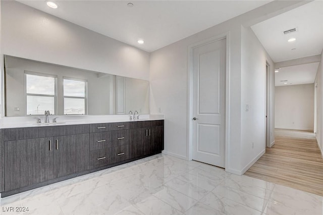 bathroom with marble finish floor, visible vents, a sink, and baseboards