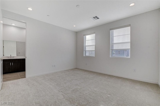 spare room with baseboards, visible vents, light colored carpet, a sink, and recessed lighting