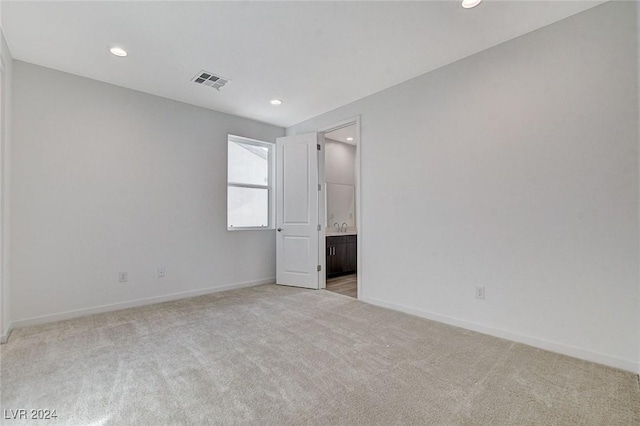 empty room featuring light carpet, recessed lighting, visible vents, and baseboards