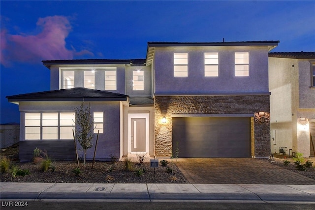 view of front of house featuring decorative driveway, an attached garage, and stucco siding