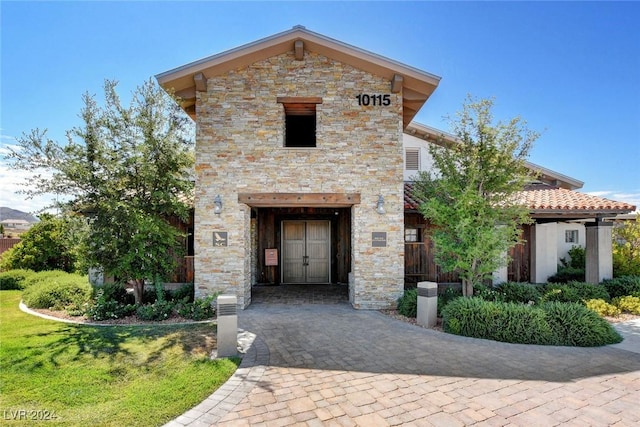 view of front of home with stone siding and a front lawn