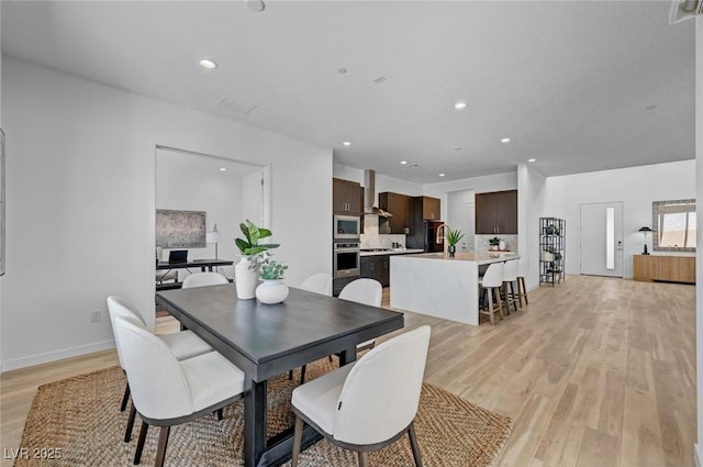 dining space featuring light wood-style floors, baseboards, and recessed lighting