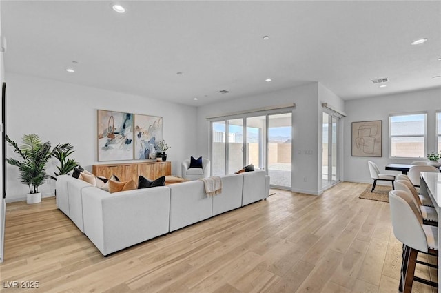 living area featuring recessed lighting, visible vents, light wood-style flooring, and baseboards