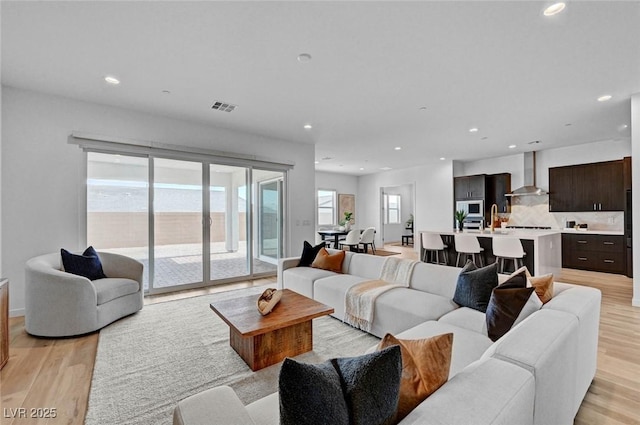 living area featuring light wood-style floors, recessed lighting, and visible vents