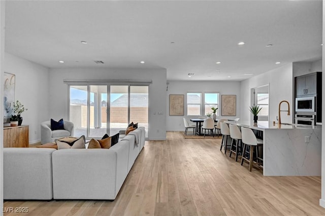 living area with recessed lighting, visible vents, and light wood-style flooring