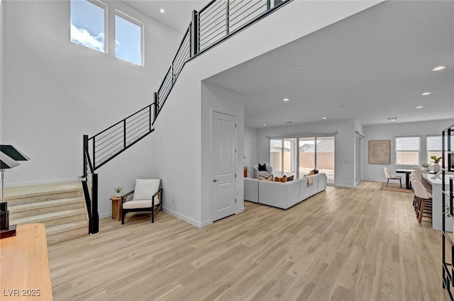 living room featuring recessed lighting, a healthy amount of sunlight, stairway, and light wood finished floors