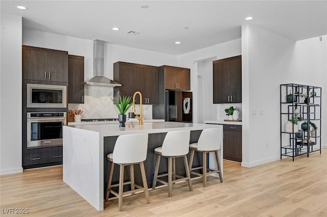 kitchen featuring built in microwave, light countertops, black refrigerator, oven, and wall chimney exhaust hood