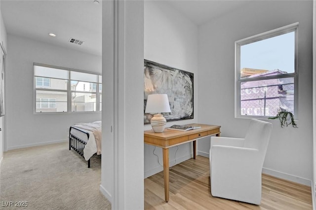 home office featuring baseboards, visible vents, light wood-style flooring, and a wealth of natural light