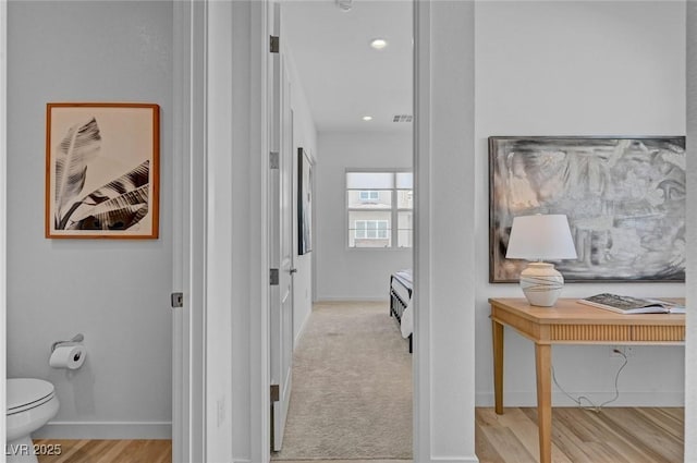 hall with visible vents, light wood finished floors, and baseboards