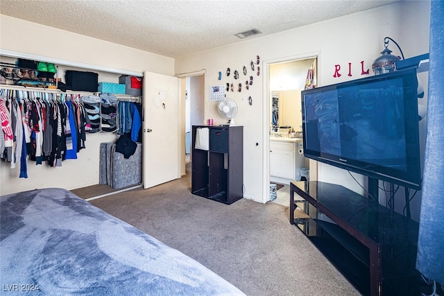 bedroom featuring dark colored carpet, a textured ceiling, ensuite bathroom, and a closet