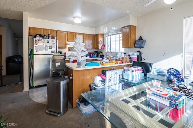 kitchen featuring carpet flooring, ceiling fan, a textured ceiling, kitchen peninsula, and stainless steel refrigerator