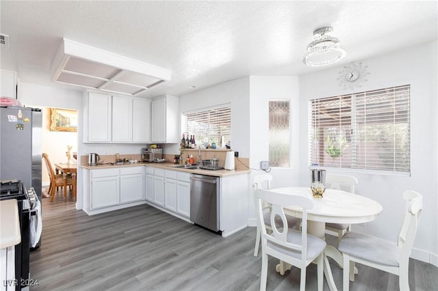 kitchen with wood-type flooring, white cabinetry, a textured ceiling, and appliances with stainless steel finishes