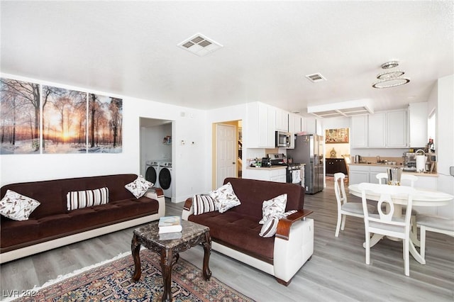 living room with independent washer and dryer and light hardwood / wood-style flooring