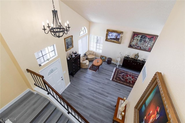 living room with a textured ceiling, dark hardwood / wood-style flooring, an inviting chandelier, and high vaulted ceiling