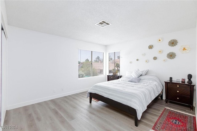 bedroom with light hardwood / wood-style floors and a textured ceiling