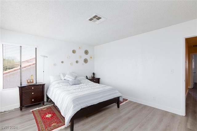 bedroom with light hardwood / wood-style floors and a textured ceiling