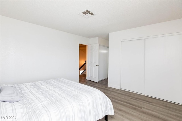 bedroom featuring hardwood / wood-style floors, a textured ceiling, and a closet