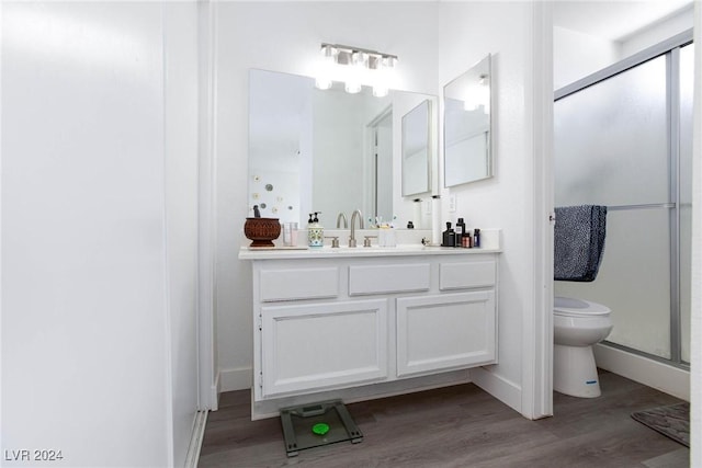 bathroom featuring hardwood / wood-style floors, vanity, toilet, and a shower with shower door