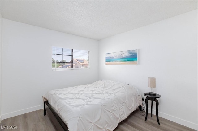 bedroom with hardwood / wood-style floors and a textured ceiling