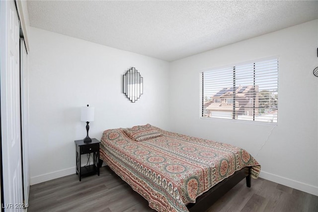 bedroom with a textured ceiling and dark wood-type flooring