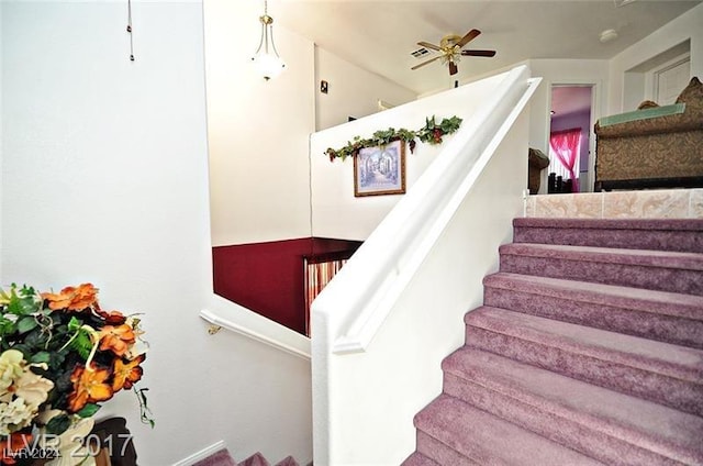 stairs featuring ceiling fan