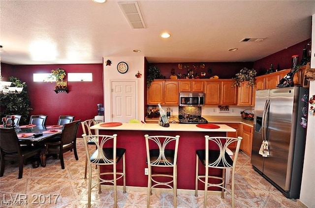 kitchen with a center island, stainless steel appliances, a breakfast bar area, and tasteful backsplash