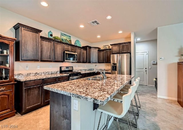 kitchen with dark brown cabinets, sink, stainless steel appliances, and a kitchen island with sink