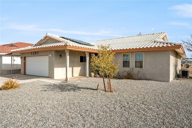 view of front of property featuring solar panels, a garage, and central air condition unit