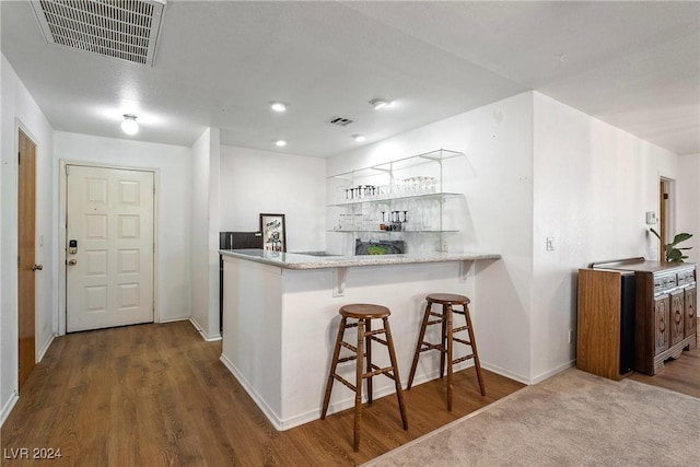 kitchen with a kitchen breakfast bar, kitchen peninsula, and wood-type flooring