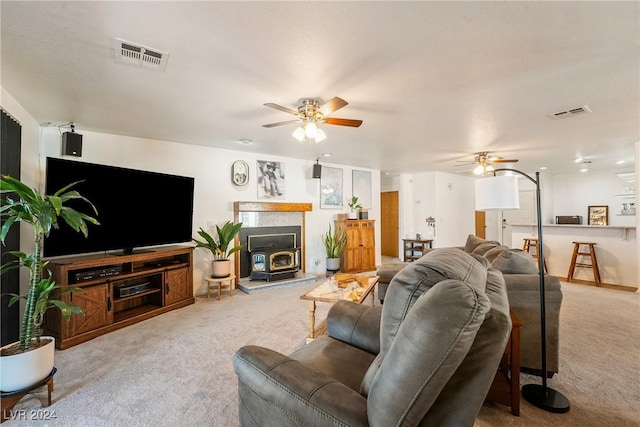 living room with light colored carpet, a wood stove, and ceiling fan