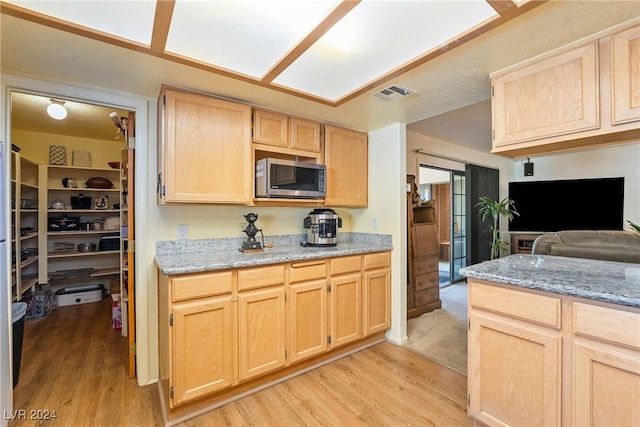 kitchen featuring light stone countertops, light brown cabinets, and light hardwood / wood-style flooring